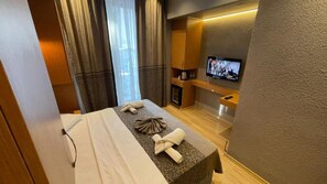 A hotel room with a massage table, a television, and a small seating area with a sofa and a coffee table. - Grand Ambiance Hotel (Istanbul)