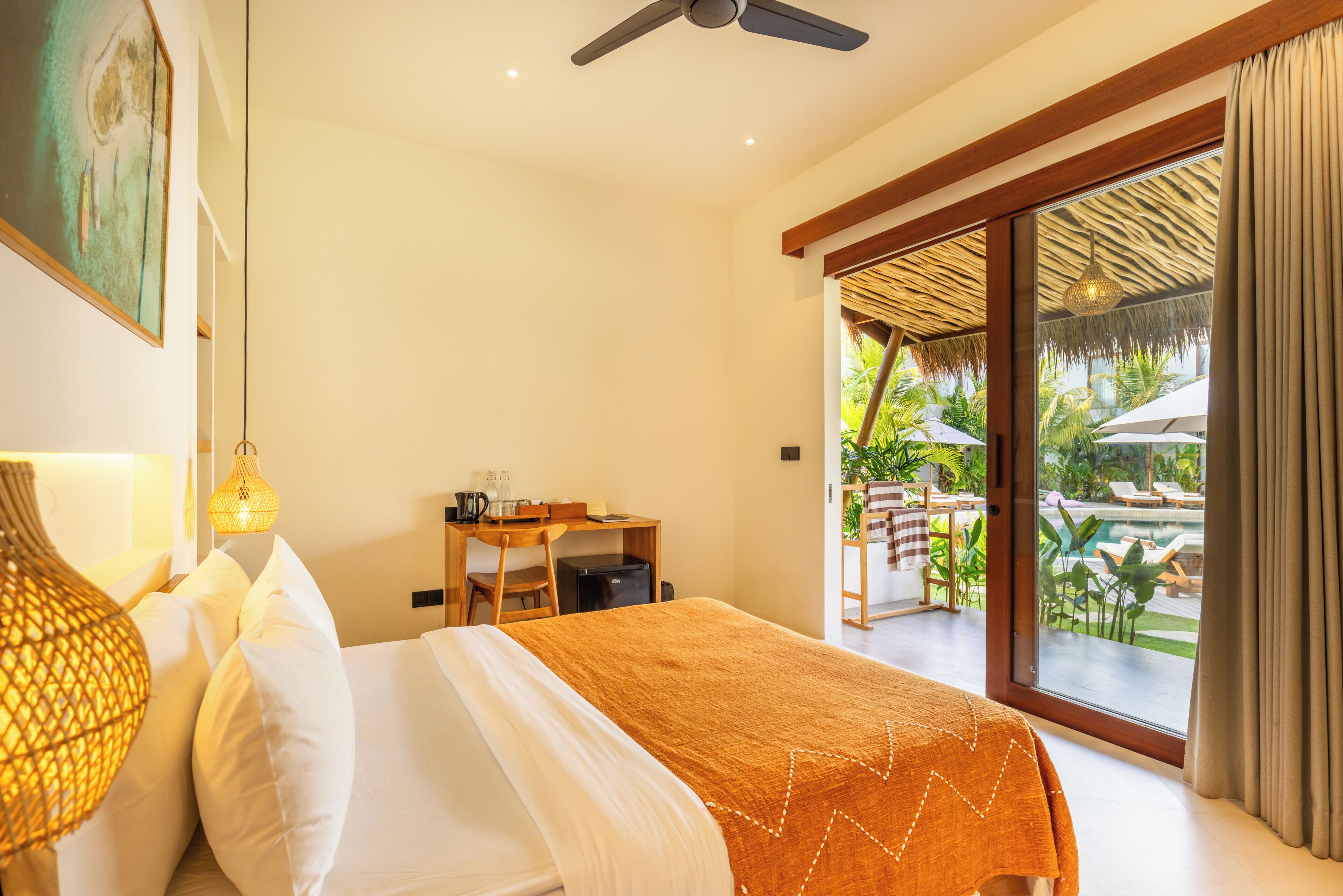 Une chambre avec un lit, un bureau et une vue sur l’espace extérieur abritant une piscine.