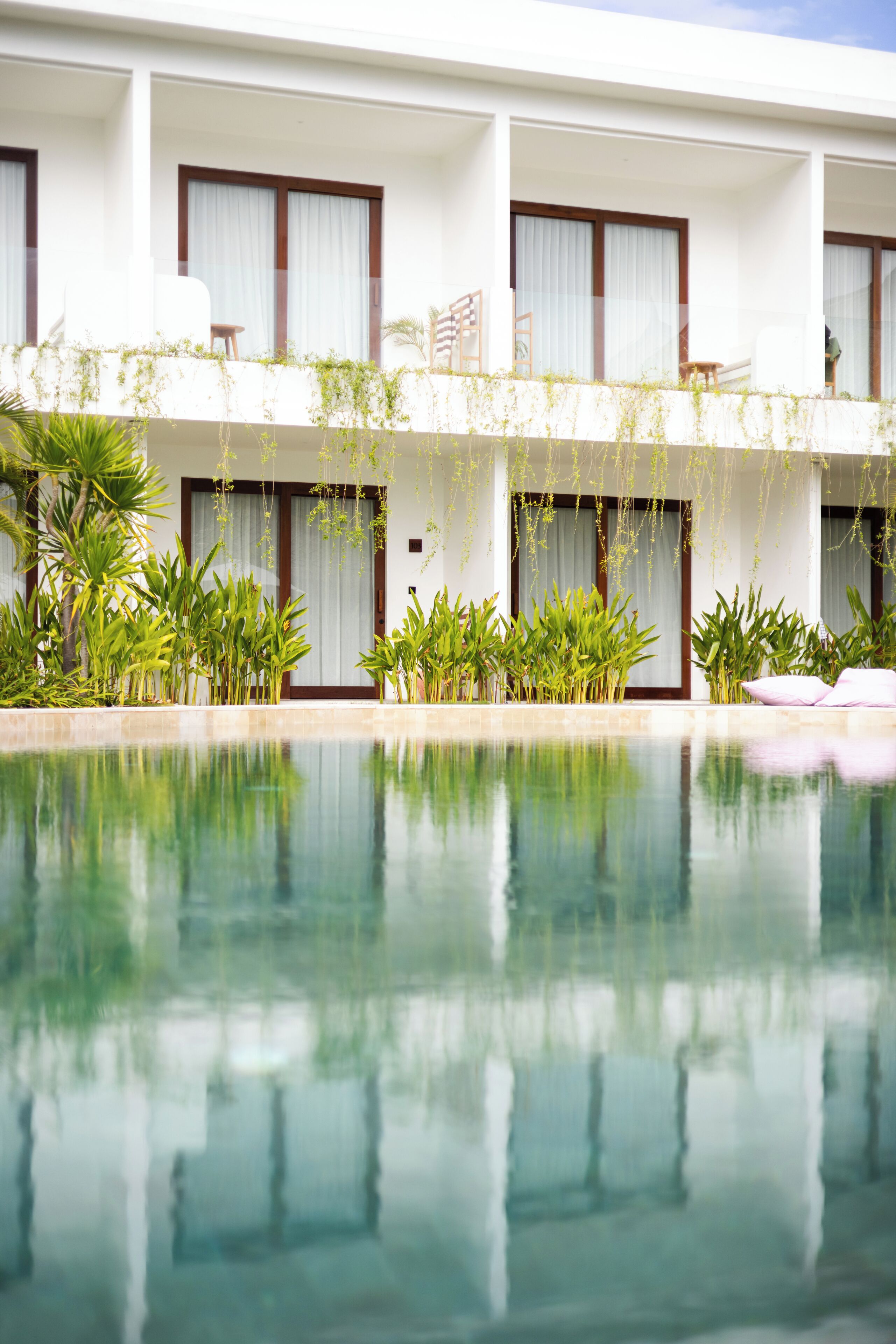 Un hôtel doté d’une piscine, de nombreux balcons et d’une végétation luxuriante.