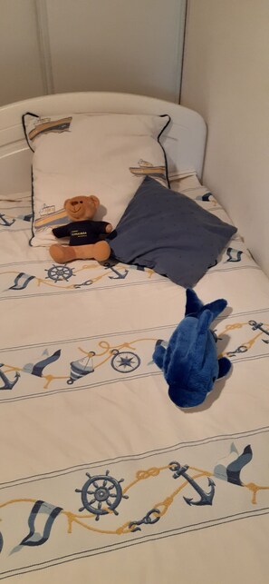 Cozy nautical-themed bed with plush toys and a matching pillow.