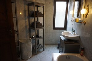 Un baño con lavamanos blanco, espejo, toallero y ventana.