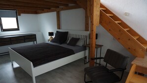 A bedroom with a bed, a chair, a desk, and a staircase. - The very special vacation apartment (Bingen am Rhein)