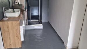 Un baño moderno con tocador de madera, un espejo grande y un lavamanos.