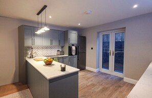 Une cuisine moderne avec des meubles gris, un îlot central et un four encastré.