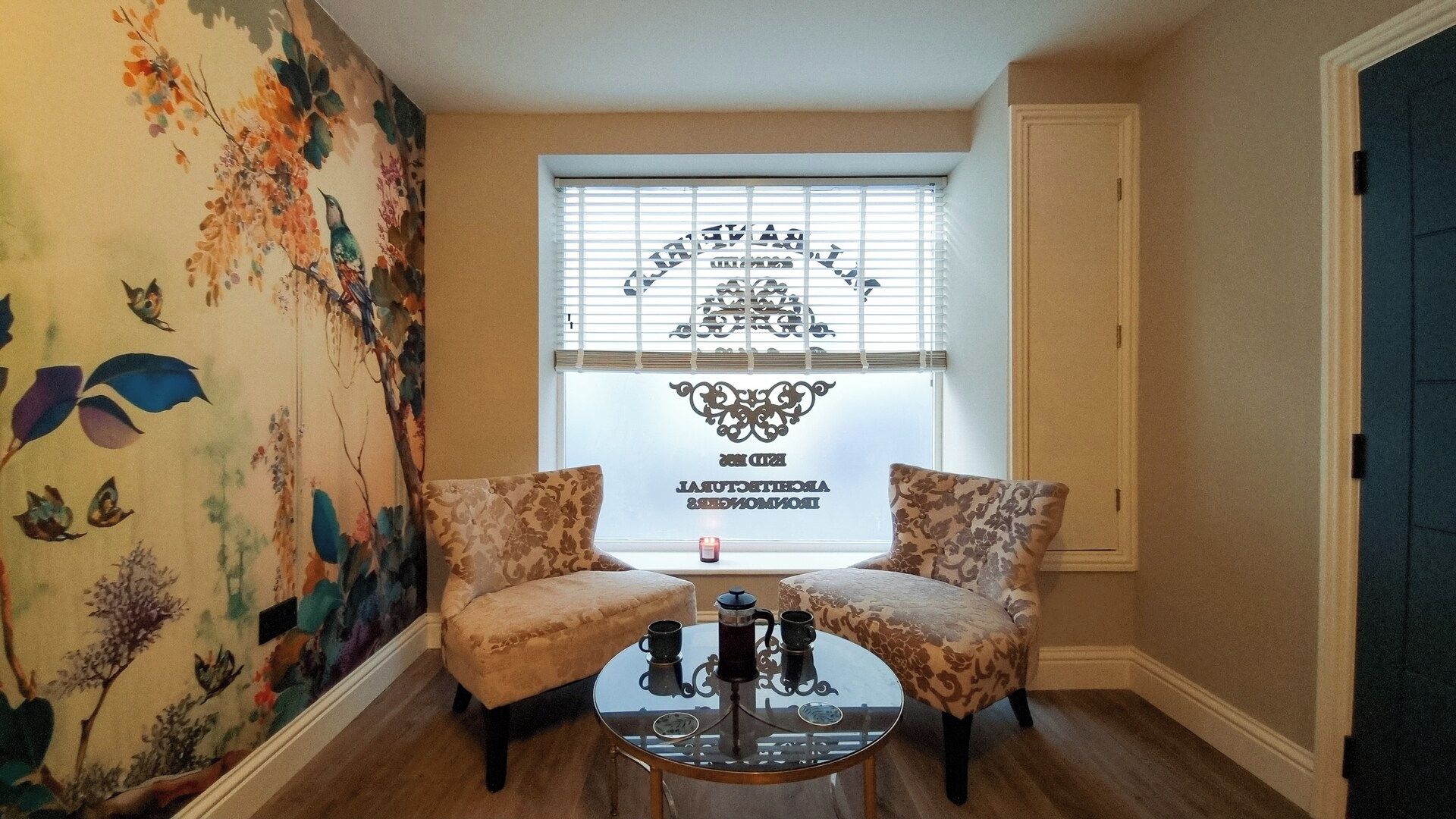 A room with two armchairs, a small round table, and a window with a decorative sticker.