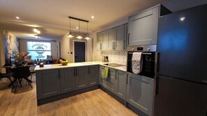 A modern kitchen with grey cabinets, a built-in oven, and a refrigerator.