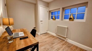 A room with a wooden table, a laptop, a lamp, and a radiator. - Heart of Brighton: 4 Bed, 4 Bath + Parking (Brighton and Hove)