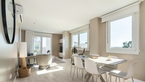 Una cocina moderna con horno empotrado, un comedor con mesa y sillas, y ventanas grandes que dejan entrar luz natural.