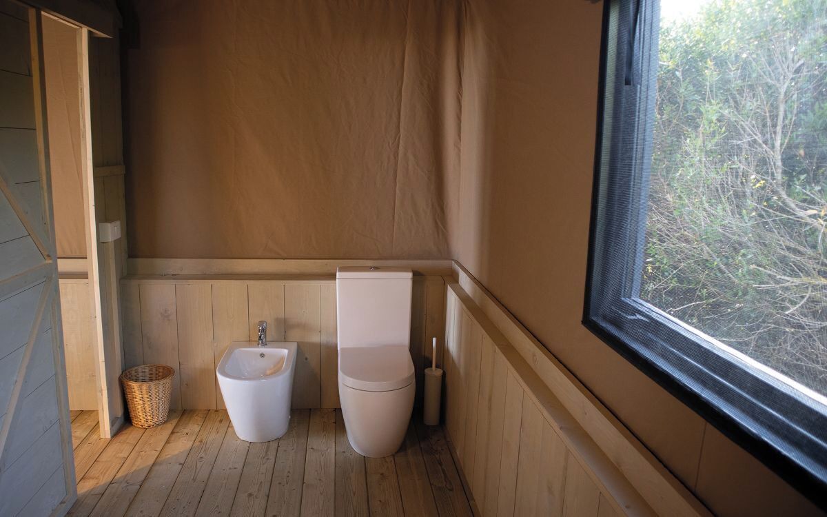Une petite salle de bain compacte, avec un plancher en bois, un lavabo et des toilettes.