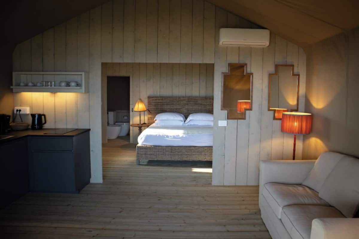 Una habitación acogedora con cama, sofá, escritorio y un espejo en la pared.