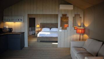 A cozy room with a bed, a sofa, a desk, and a wall-mounted mirror.