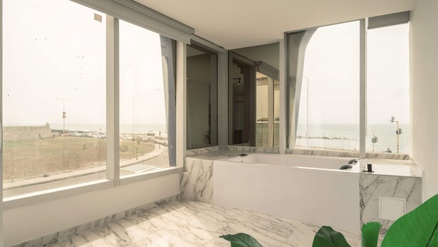 Um banheiro moderno com uma banheira grande, piso de mármore e janelas amplas com vista para o mar.