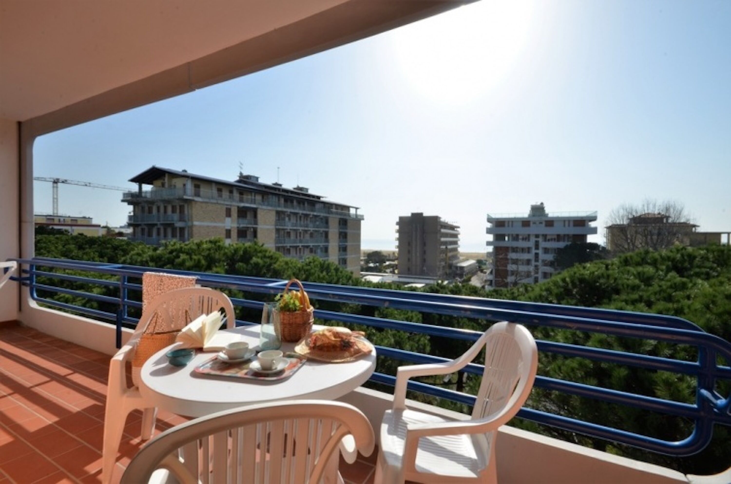 Ein Balkon mit einem Tisch für zwei Personen, Stühlen und Blick auf Gebäude und Grünflächen.