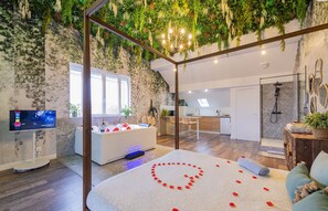 Una habitación moderna con una cama, un sillón de masajes, un televisor y una zona de ducha.