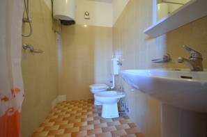 Une salle de bain équipée de toilettes, d’un bidet et d’un lavabo.
