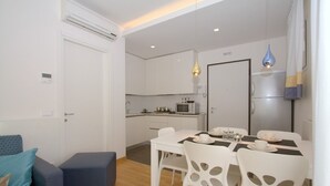 A compact living space with a dining area, kitchenette, and a small seating area with a sofa and ottoman. - Modern apartment with solarium near the beach (Bibione)