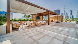 Een buitenruimte met een overdekt gedeelte, een stadsachtergrond en uitzicht op de Burj Khalifa.