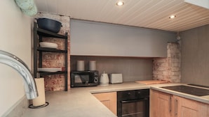 Une cuisine compacte équipée d’un évier, d’une cuisinière, d’un four à micro-ondes, d’un grille-pain et d’un mur en briques.