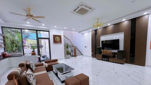 Ein modernes Wohnzimmer mit einem großen Fernseher, einem Deckenventilator und einer Treppe, die zu einer anderen Ebene führt.