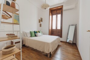A bedroom with a wooden bed, white bedding, a standing mirror, and a wooden wardrobe. - Loft by Melo - Seaview terrace (Siracusa)