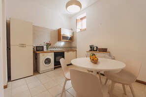 A compact kitchen with a washing machine, microwave, and a small dining table with chairs. - Loft by Melo - Seaview terrace (Siracusa)