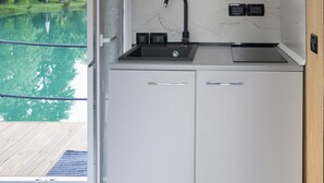 Una cucina compatta con lavello incassato, pannello paraschizzi in legno e vista su una piscina.