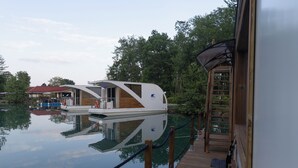Una casa galleggiante ormeggiata a un pontile, con terrazza in legno e piccolo spazio esterno.