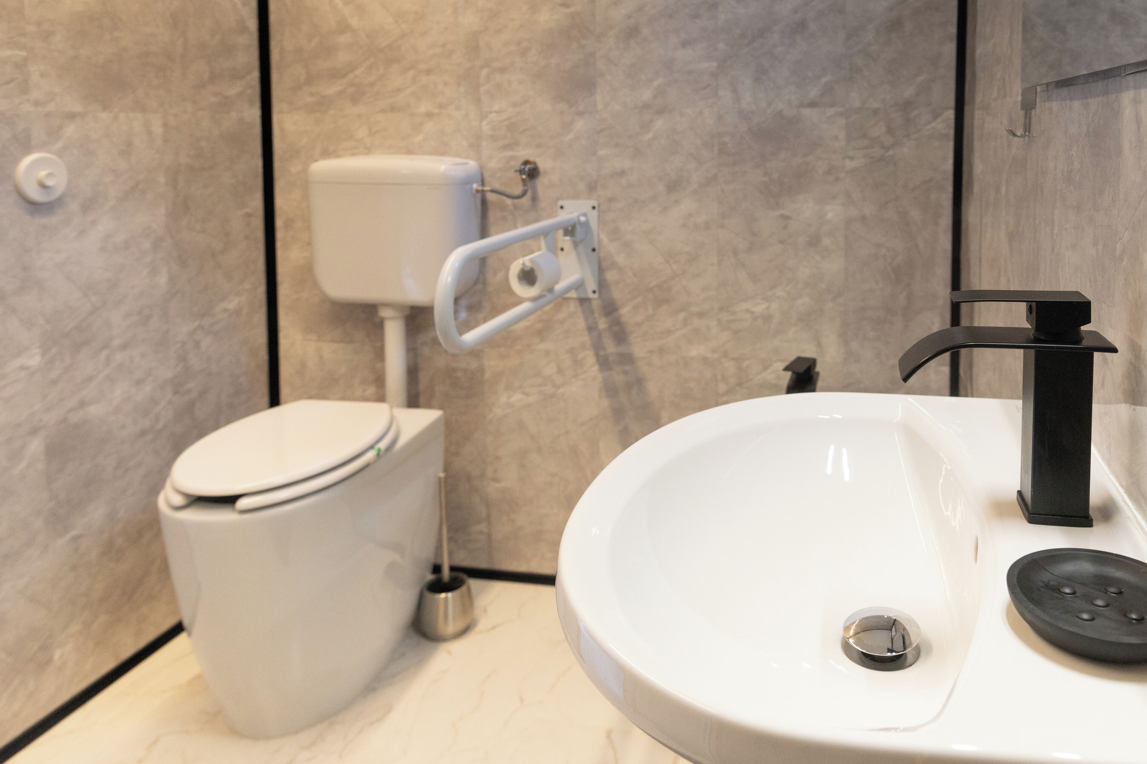 Et moderne badeværelse med toilet, vask og toiletpapirholder.