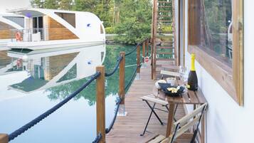 A wooden deck with a table, a bottle, and a chair.