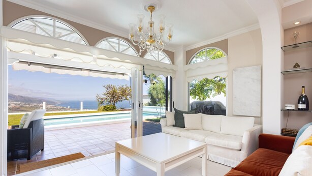 A spacious living area with a white sofa, a coffee table, and a view of a pool and landscape. - 4 bedroom house with pool, garden and beautiful views of the valley and the sea. (Santa Úrsula)