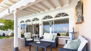 An outdoor patio with wicker furniture, a tiled floor, and a view of the cityscape. - 4 bedroom house with pool, garden and beautiful views of the valley and the sea. (Santa Úrsula)