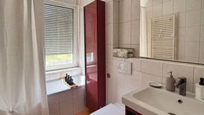 Une salle de bain moderne équipée de toilettes, d’un lavabo et d’une fenêtre avec stores.