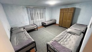 A dormitory room with two single beds, a wooden wardrobe, and a window with curtains. - Jakesh (Karakol)