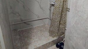 A small, enclosed shower area with a marble wall, a window, and a shower curtain. - Jakesh (Karakol)