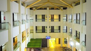 A multi-level hotel interior with a central atrium, glass railings, and a visible fire extinguisher. - Ambar Sarovar Portico (Gandhidham)