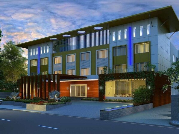 A modern building with a flat roof, multiple windows, and a landscaped entrance. - Ambar Sarovar Portico (Gandhidham)