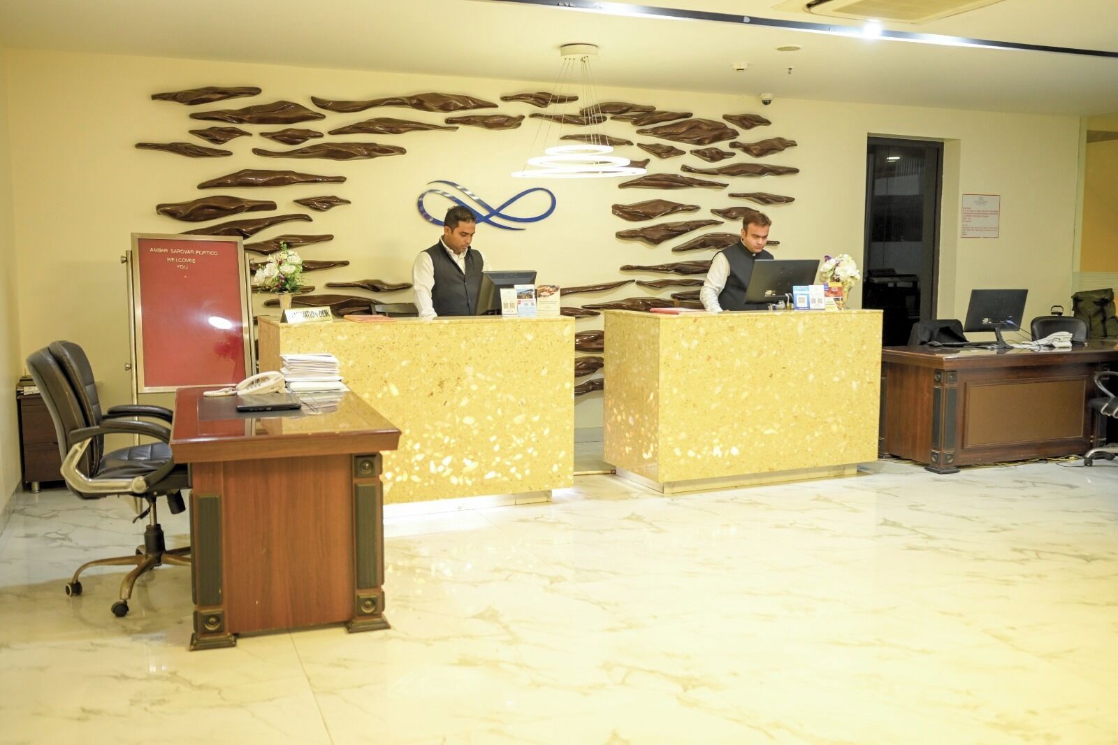 A reception area with a receptionist desk, a computer, and a wall with fish-shaped decorations.