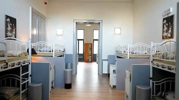 A dormitory room with bunk beds, a hallway, and a door leading to another room.