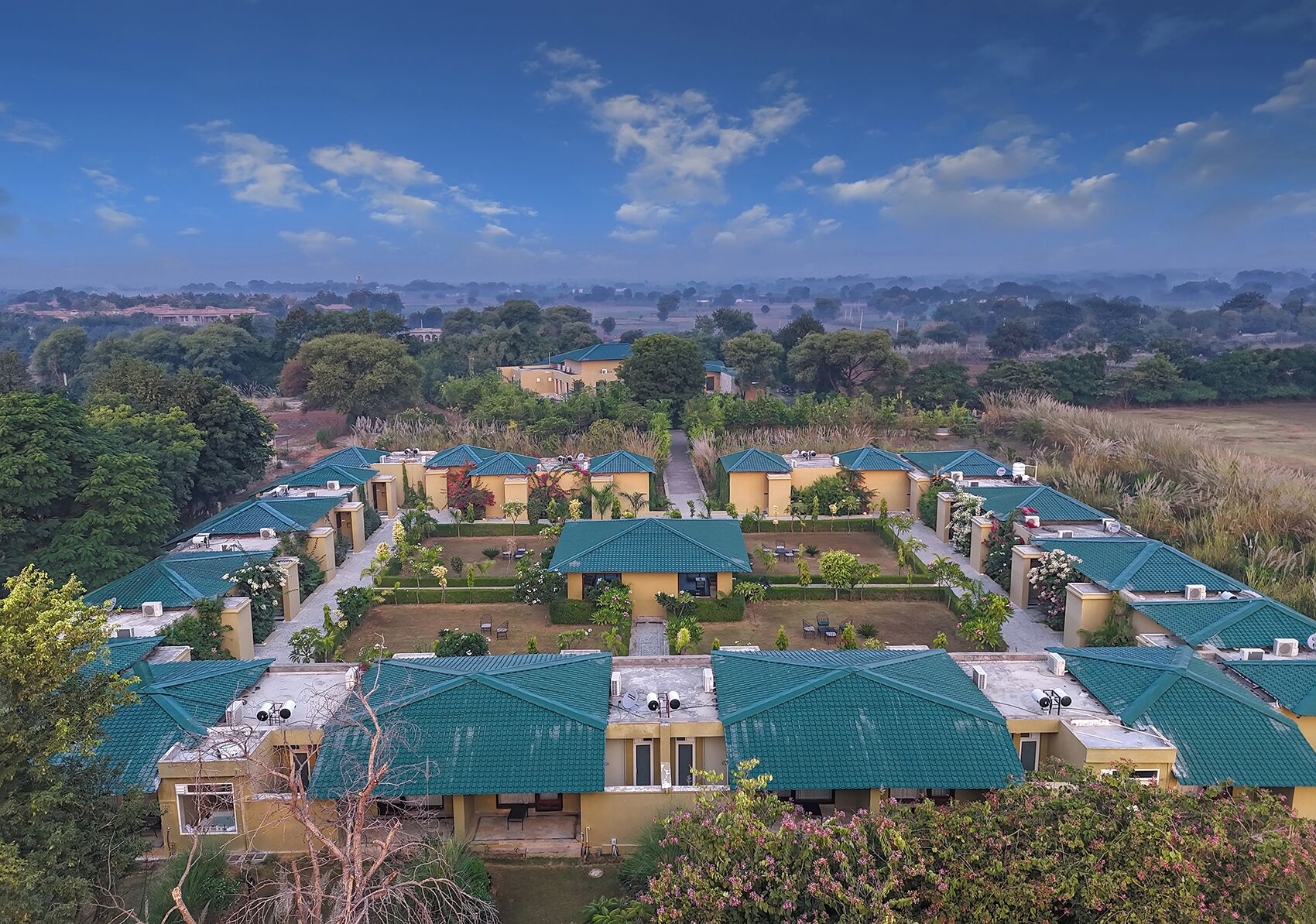 A resort with multiple buildings, each with a green roof and surrounded by well-maintained gardens.