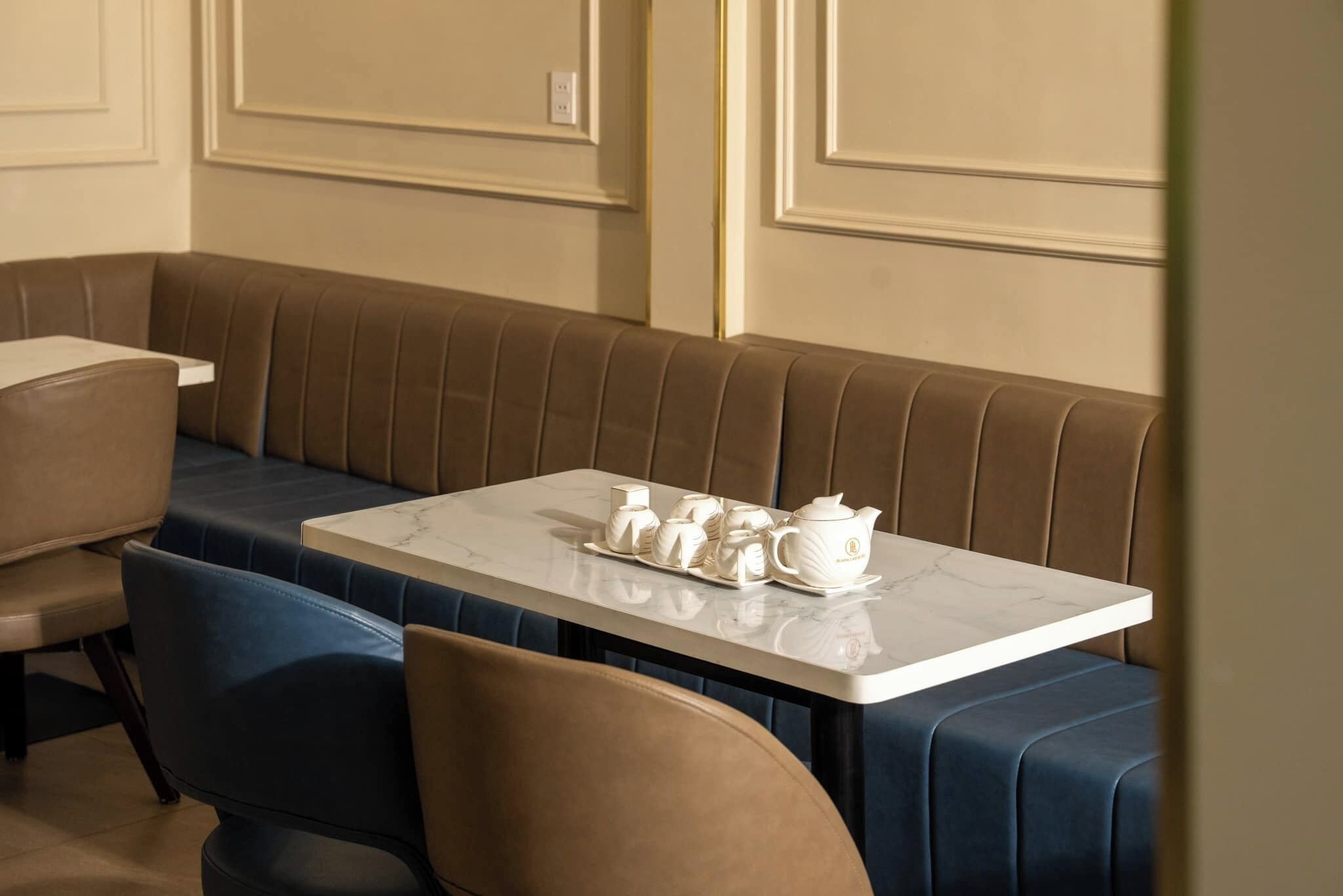 A seating area with a table set for tea, cushioned benches, and a marble table.