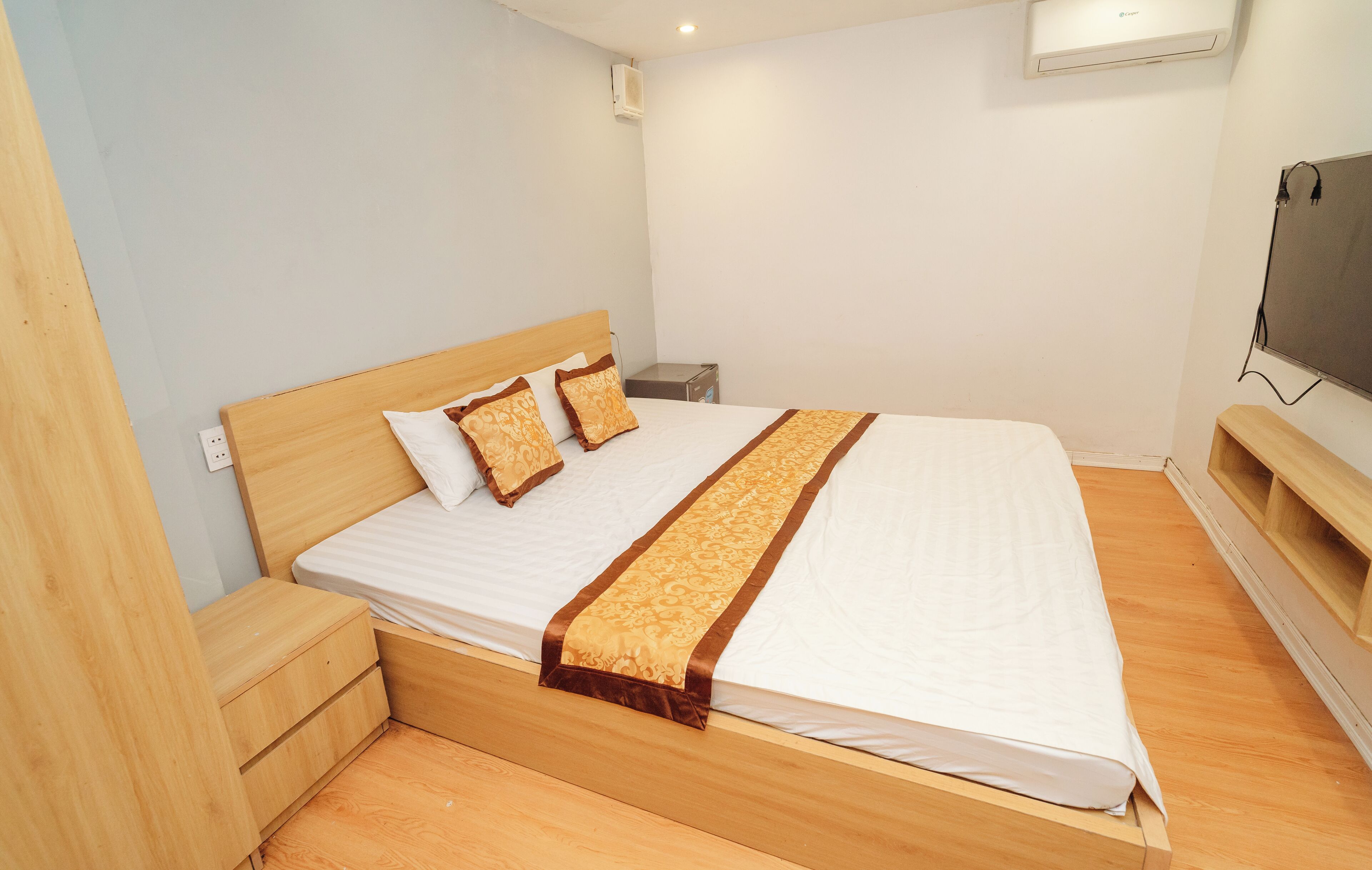 A neatly made bed with a wooden headboard, two pillows, and a decorative bed runner.