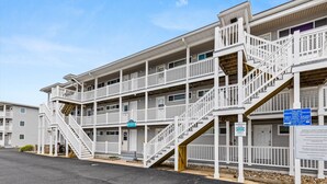 Un motel à plusieurs étages, doté d’un escalier central, d’un panneau indiquant l’emplacement du parking et d’un panneau d’information bleu.