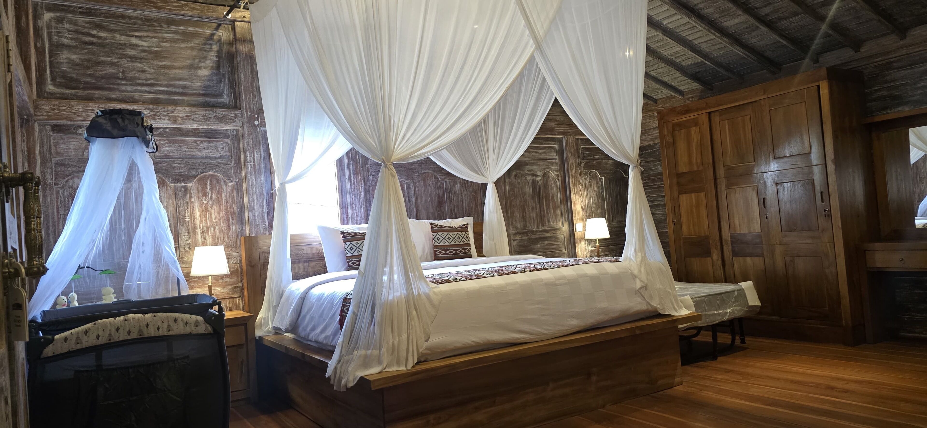 Un dormitorio de madera con cama con dosel, mesita de noche, lámpara y armario.