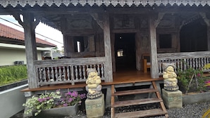 A wooden structure with a porch, decorative statues, and potted plants. - Mara Inn (Nusa Dua)