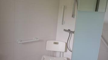 Een badkamer met douche, toilet en een greep.