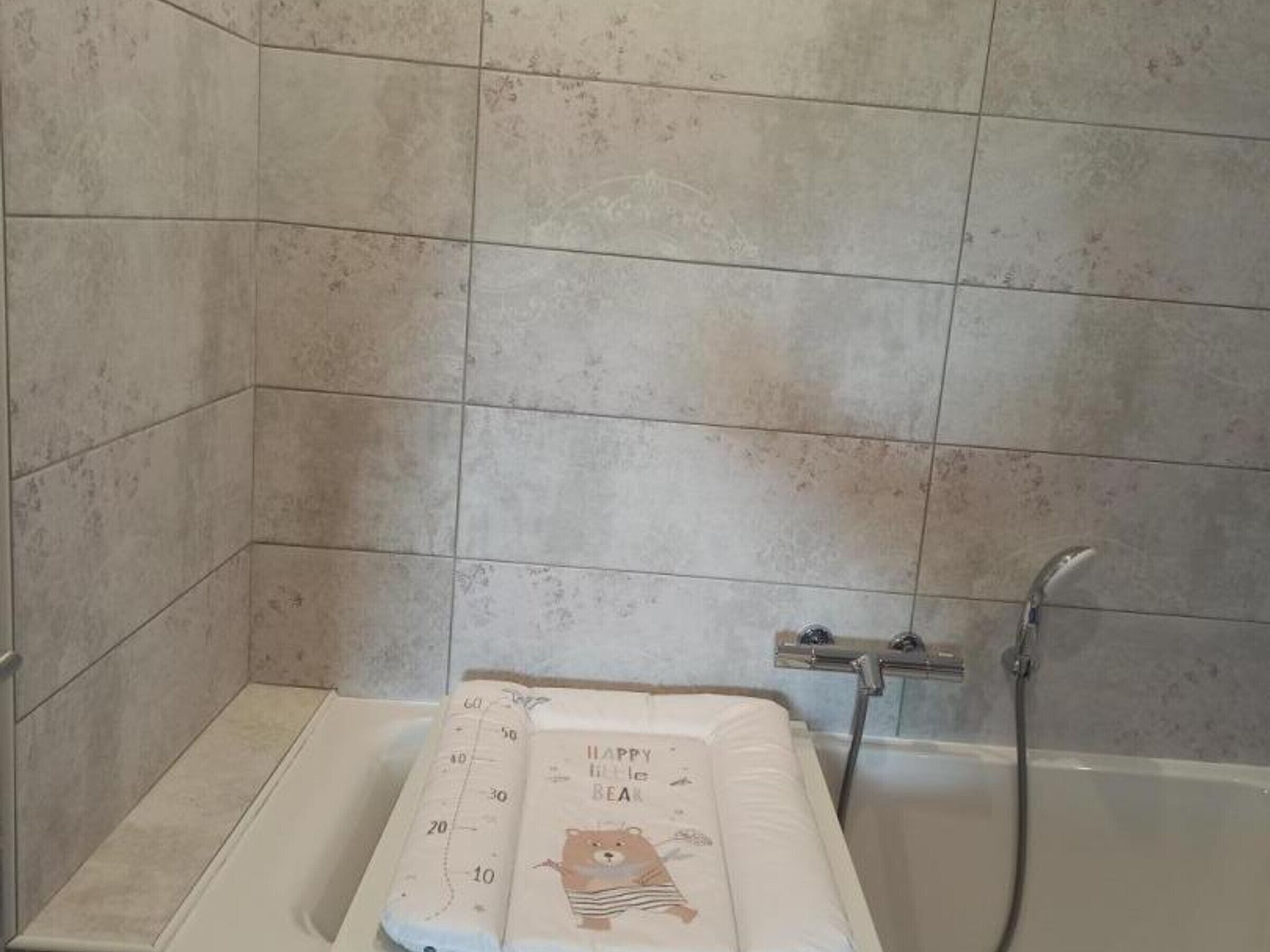 Kylpyhuone, jossa on kylpyamme, suihku ja karhukuviollinen pyyhe.