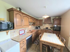 A kitchen with wooden cabinets, a microwave, a dishwasher, a sink, and a table with chairs.