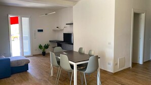 Una sala de estar moderna con una mesa de comedor, sillas, un sofá y un televisor.