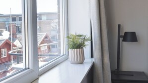 A room with a large window, a potted plant, a desk, and a lamp. - Victoria hotell Fredrikstad (Fredrikstad)