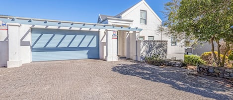 A residential property with a paved driveway, a garage, and a stone wall.